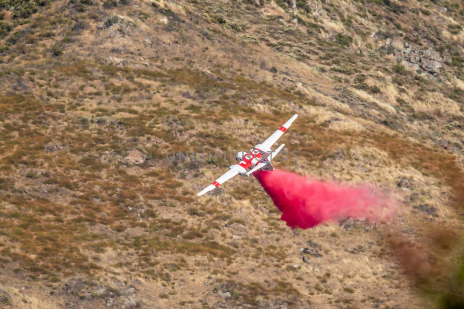 Winchester, CA USA - June 14, 2020: Cal Fire aircraft drops fire retardant on a dry hilltop wildfire near Winchester, California. by Feverpitched