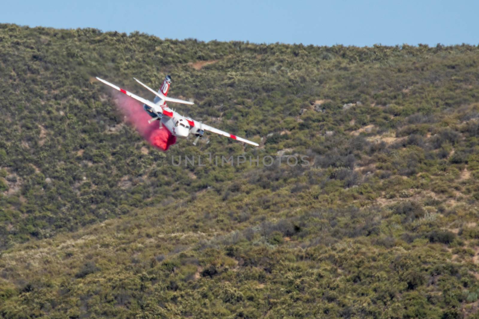 Winchester, CA USA - June 14, 2020: Cal Fire aircraft drops fire retardant on a dry hilltop wildfire near Winchester, California. by Feverpitched