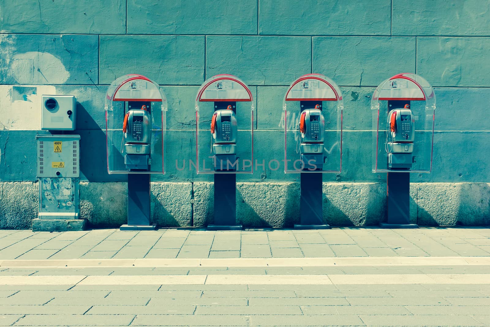Four phone booths by the wall. Trieste, Italy