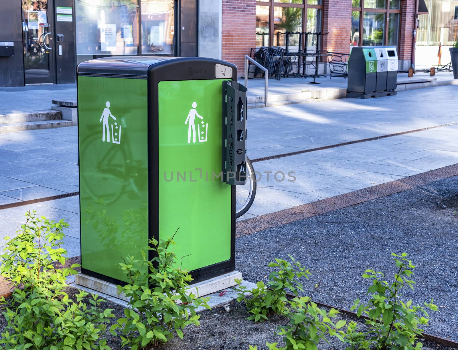 UMEA, SWEDEN - JUNE 10, 2020: Fresh nice looking green bin with black top, easy cans recycling for tourists and locals walking on street, summer time, central part of Umea city, Vasterbotten county
