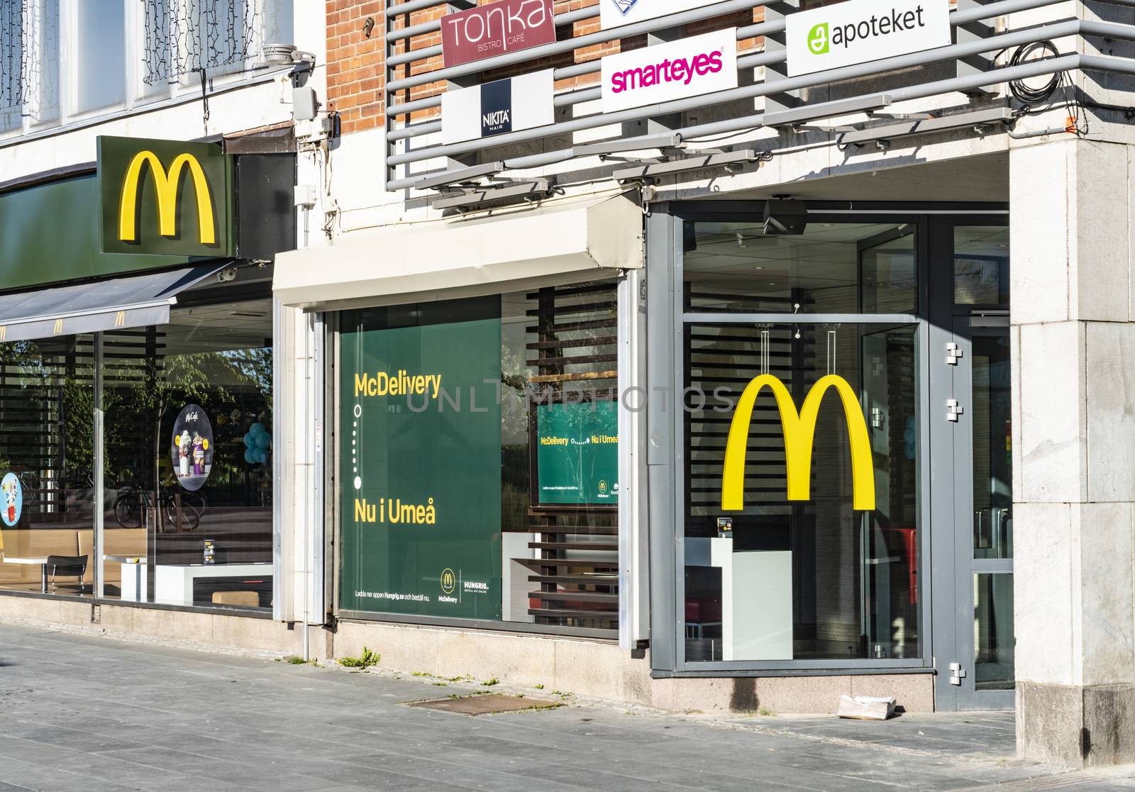 UMEA, SWEDEN - JUNE 10, 2020: Two bright classical yellow McDonalds Logos in Umea downtown on Radhustorget Square, sunny summer day. Fast food restaurant, Vasterbotten by skydreamliner