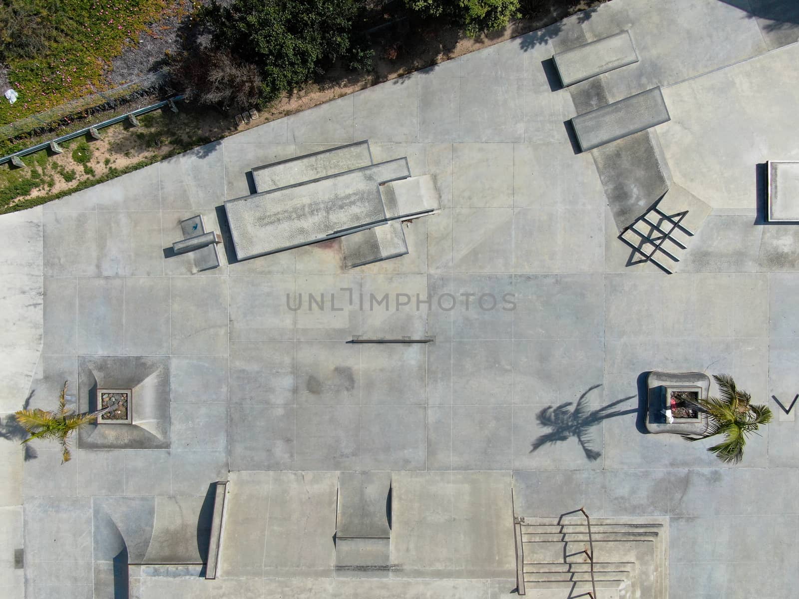 Aerial view of outdoor empty concrete skate park with ramps and pipes in California. USA