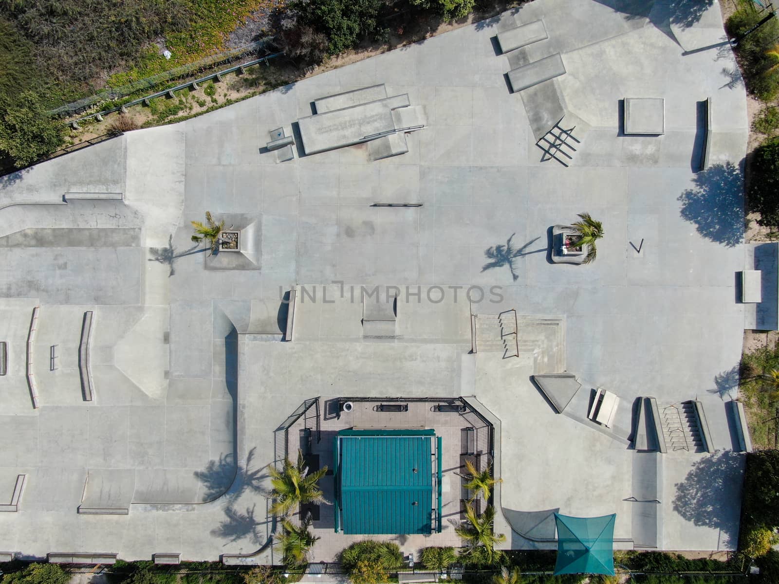 Aerial view of outdoor empty concrete skate park with ramps and pipes in California. USA