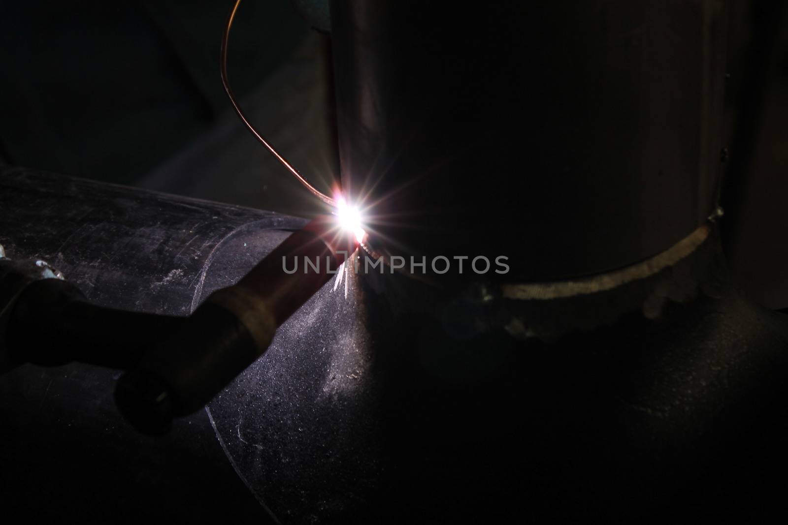 Welder Worker Performs Jump Welding. Worker Welder Performs Arc-Welding Process of Metal Structures. Flying Sparks From the Welding Machine. Welder Welds Metal Profiles for Second Floor Indoors