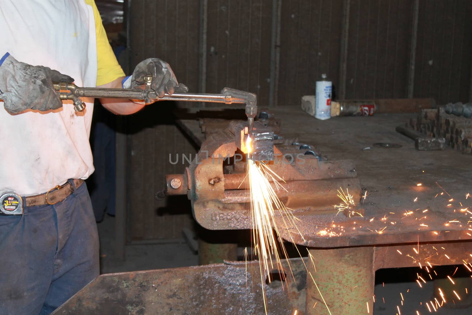 Worker is cutting manually old metal construction in container by using gas mixture of oxygen and acetylene, propane for repair work.