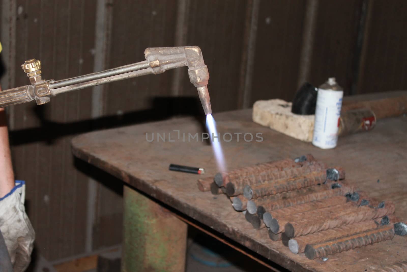 Worker is cutting manually old metal construction in container by using gas mixture of oxygen and acetylene, propane for repair work.