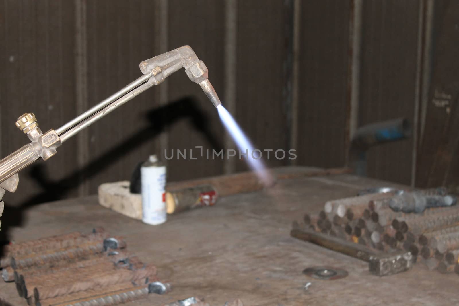 Worker is cutting manually old metal construction in container by using gas mixture of oxygen and acetylene, propane for repair work.