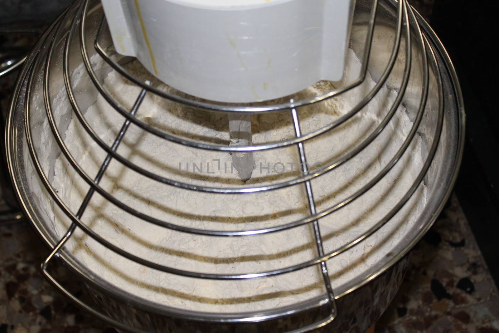 Mixing dough for bread baking with professional kneader spiral machine at the manufacturing. The dough is kneaded for burgers.