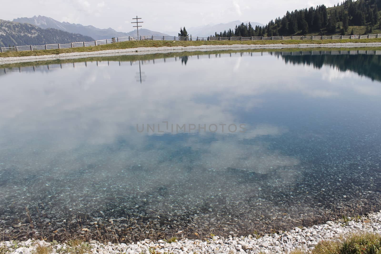 Scenic view to small alpine lake and big mountains with glacier in sunlight. Awesome green landscape with blue mountain lake among mosses in green highland valley in sunny day. Wonderful scenery.