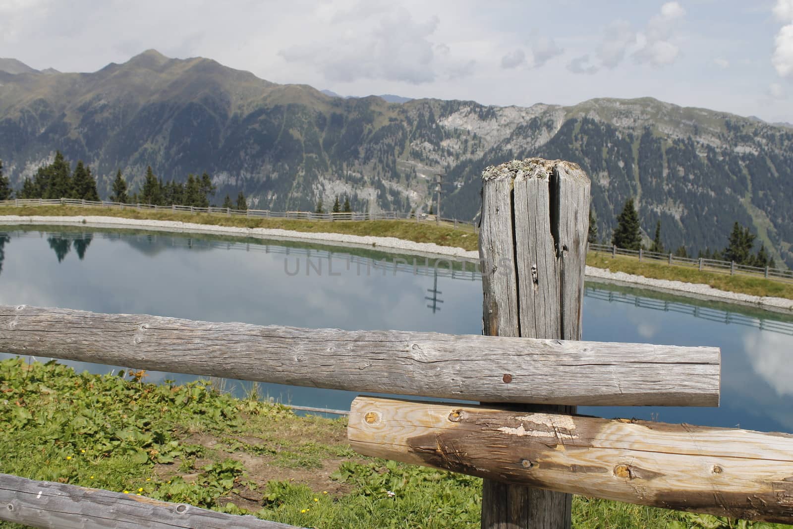 Scenic view to small alpine lake and big mountains with glacier in sunlight. Awesome green landscape with blue mountain lake among mosses in green highland valley in sunny day. Wonderful scenery.