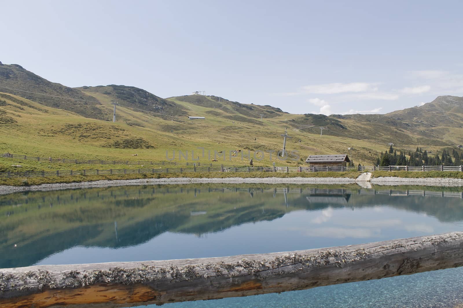 Scenic view to small alpine lake and big mountains with glacier in sunlight. Awesome green landscape with blue mountain lake among mosses in green highland valley in sunny day. Wonderful scenery.