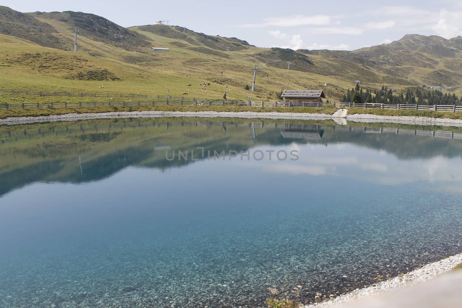 Scenic view to small alpine lake and big mountains with glacier in sunlight. Awesome green landscape with blue mountain lake among mosses in green highland valley in sunny day. Wonderful scenery.