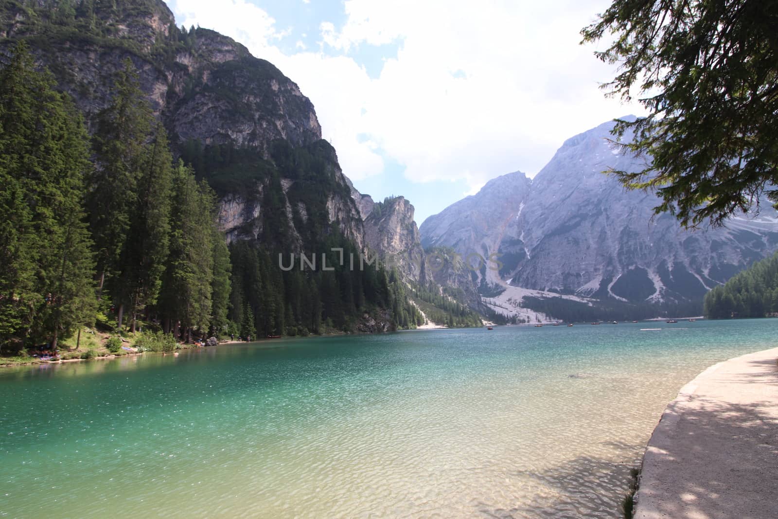 Braies Lake in Dolomites mountains forest trail in background, Sudtirol, Italy. Lake Braies is also known as Lago di Braies. The lake is surrounded by forest which are famous for scenic hiking trails.