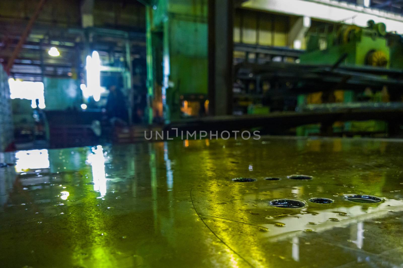 defocused abstract old factory background and oily horizontal steel surface in foreground.