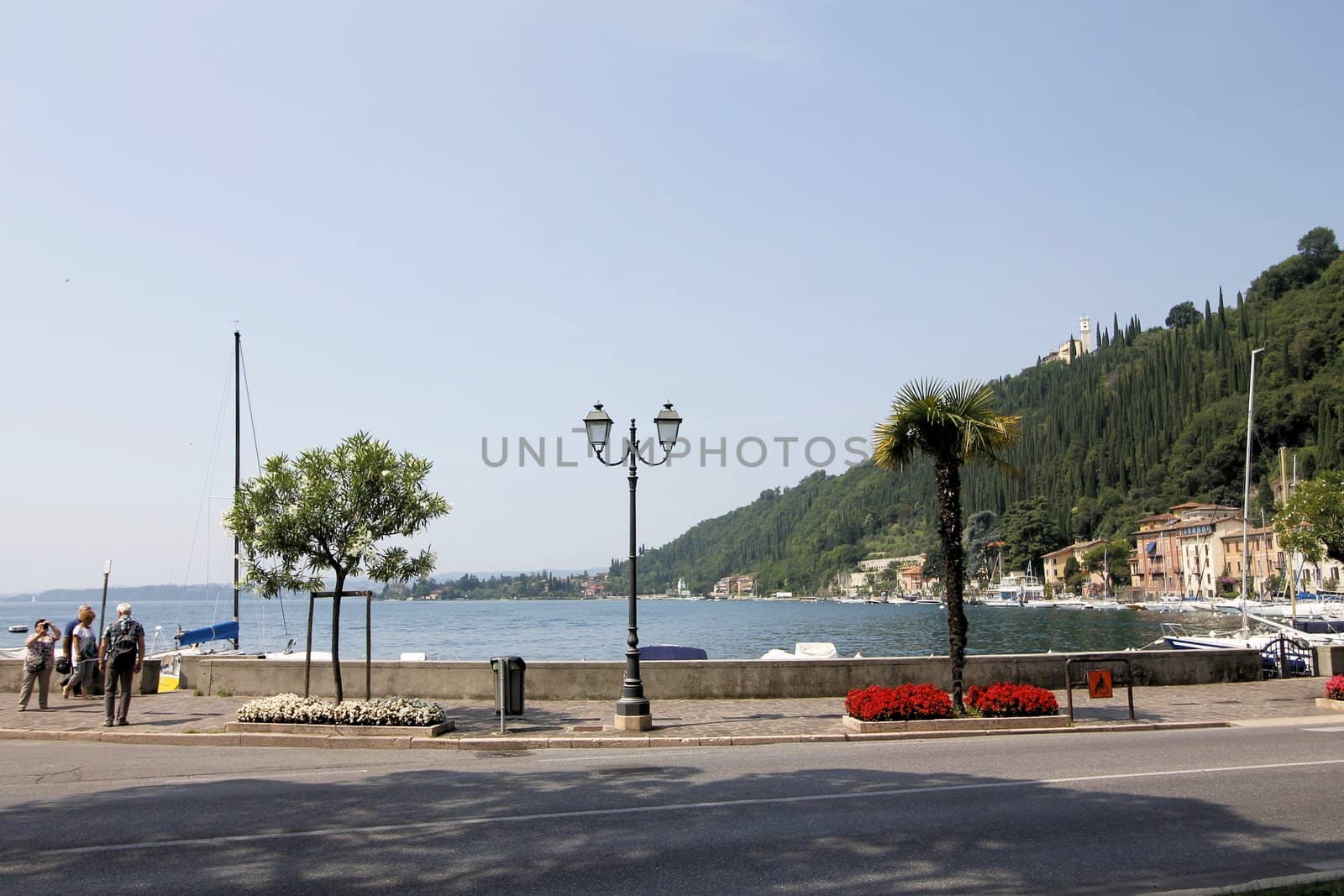 Scenic panoramic beltway road around lake Garda with medieval architecture buildings and rich northern Italy trees and plants growing on coast