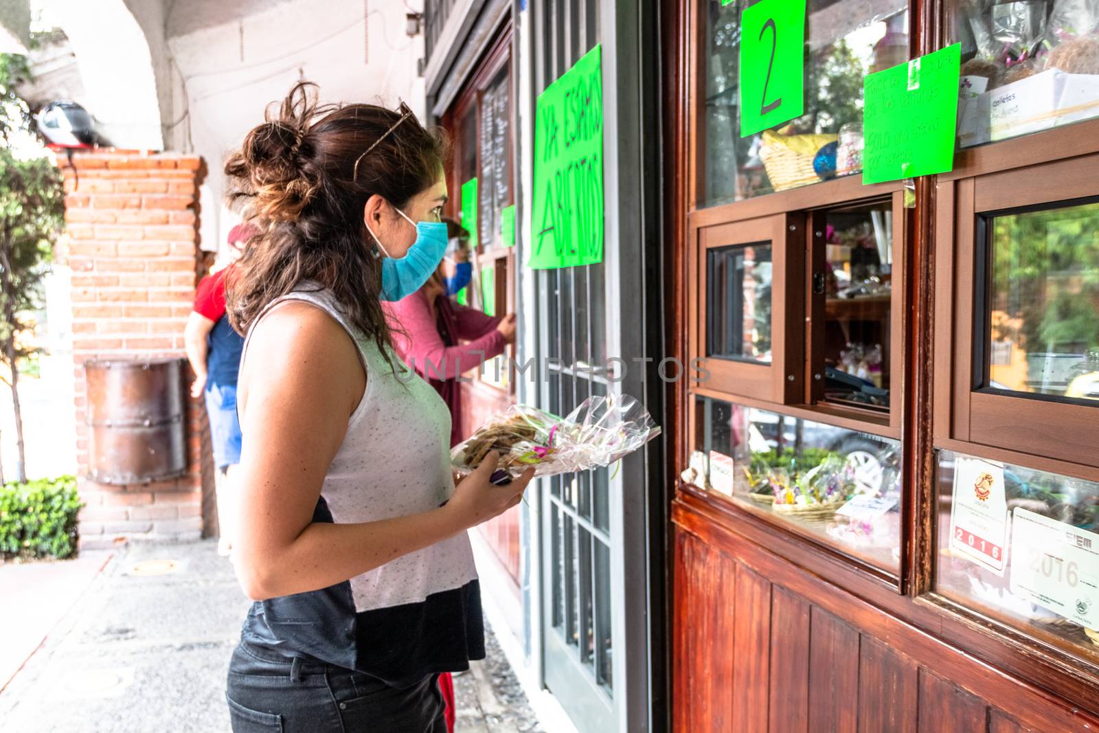 Alvaro Obregon, CDMX. Mexico. June 10, 2020. Woman buys cookies with surgical mask for the new normal. by leo_de_la_garza