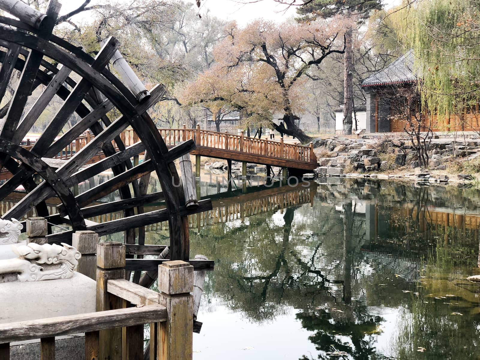 Water mill wheel in a calm little river and little pavilion on the background at The Imperial Summer Palace of The Mountain Resort in Chengde. China. 