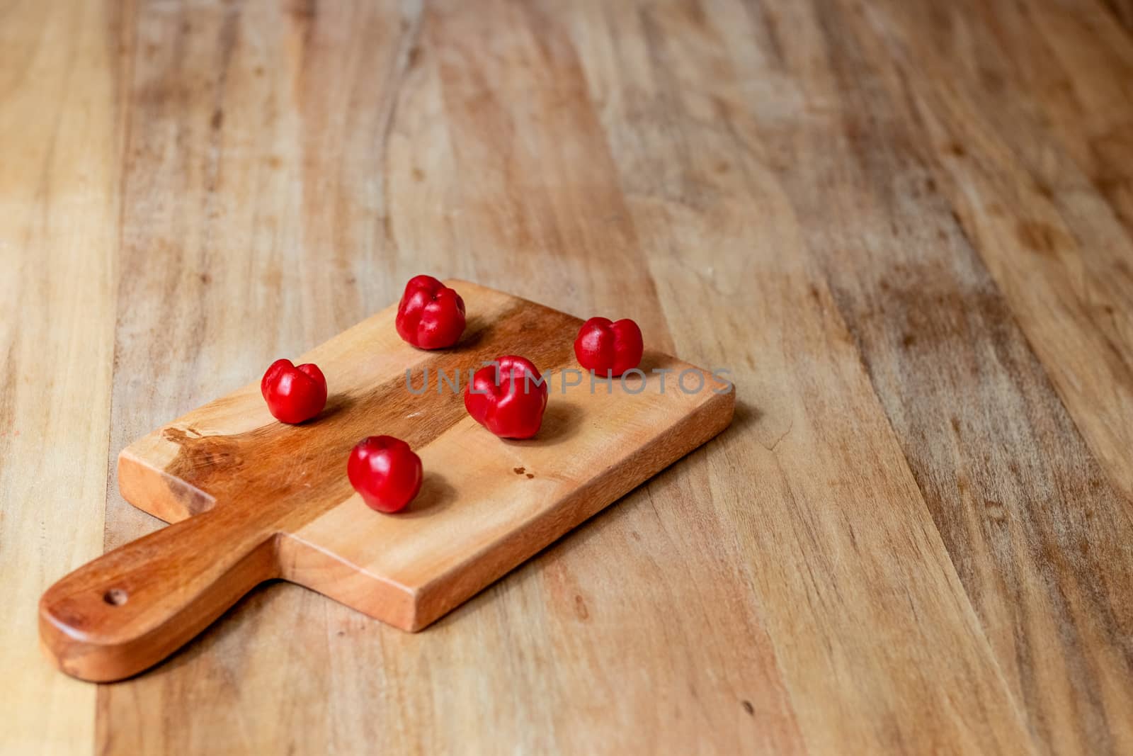 Apple and serrano peppers on chopping board on wooden surface. copy space