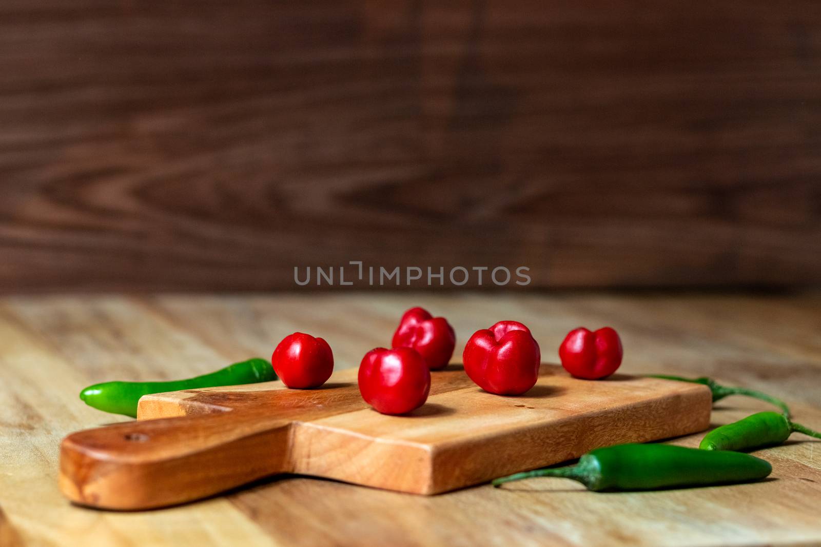 Apple and serrano peppers on chopping board on wooden surface. copy space