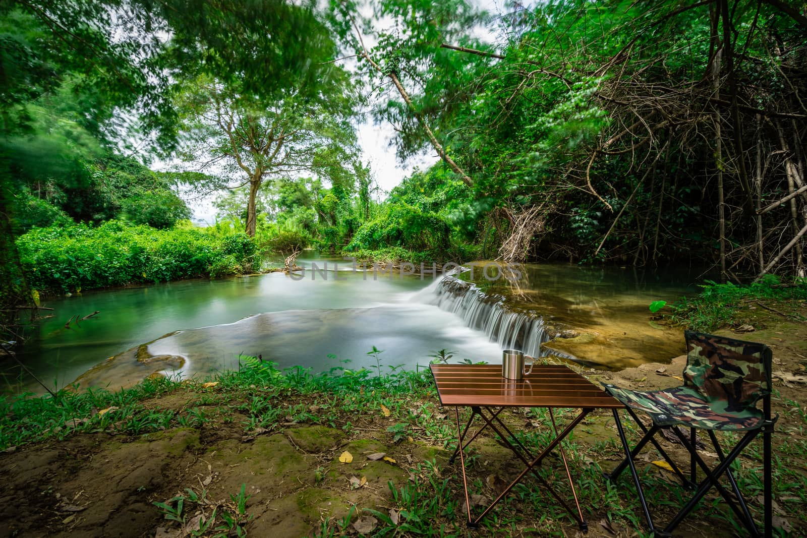 Camping chair with table in front of the waterfall on holiday