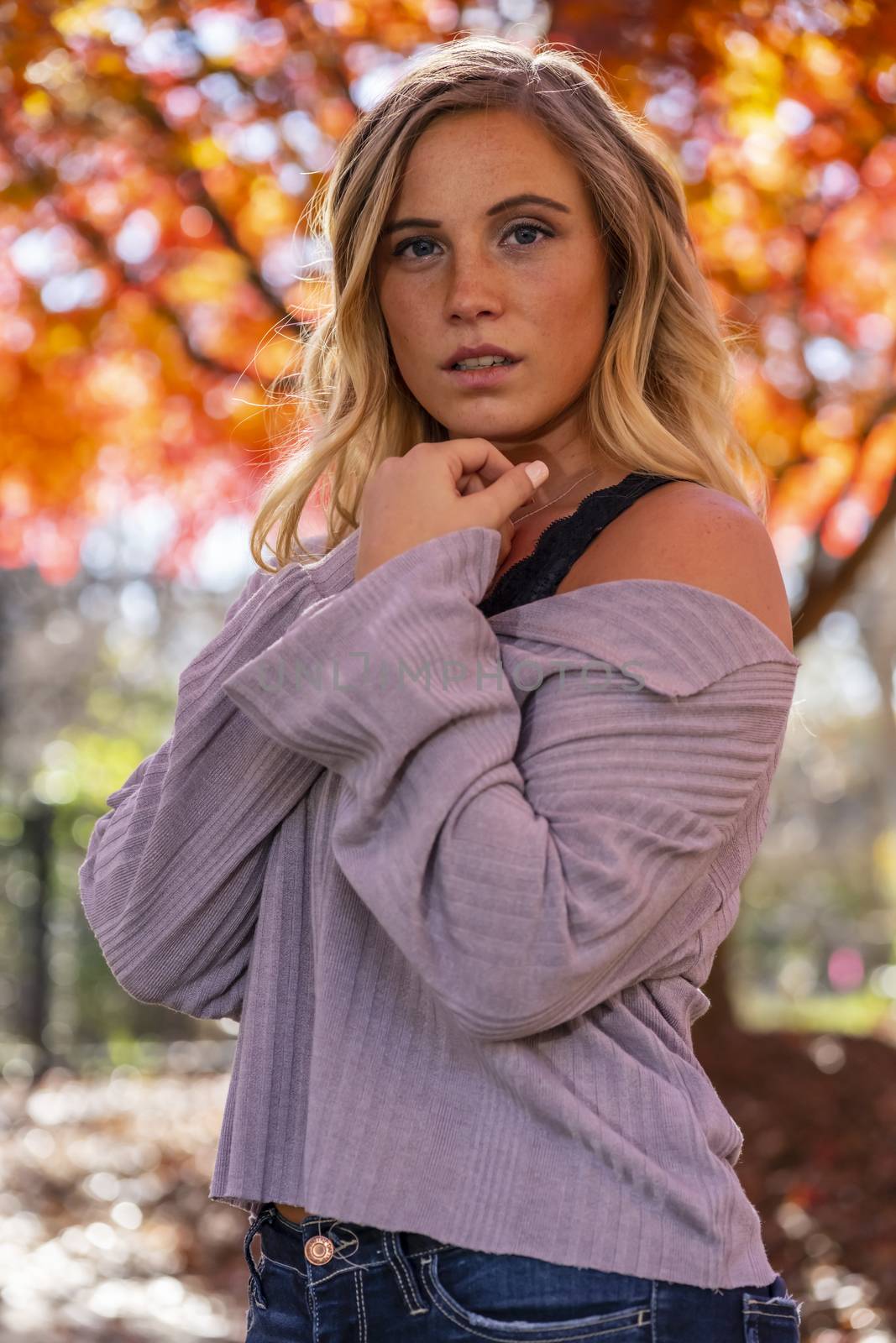 A gorgeous blonde model enjoys a Autumn day outdoors in a park