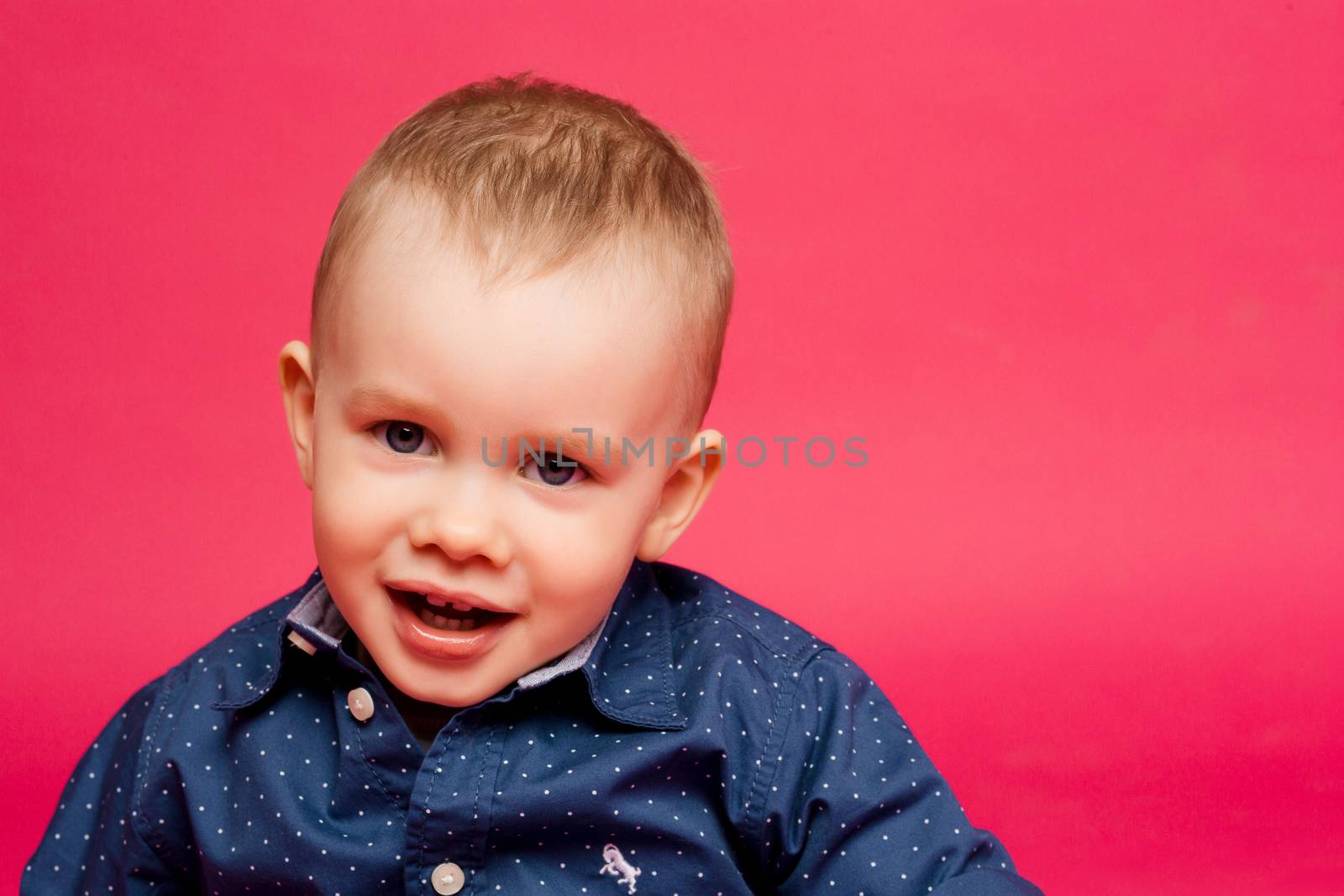 Happy little boy in dark blue shirt smiling at camera. by StudioLucky