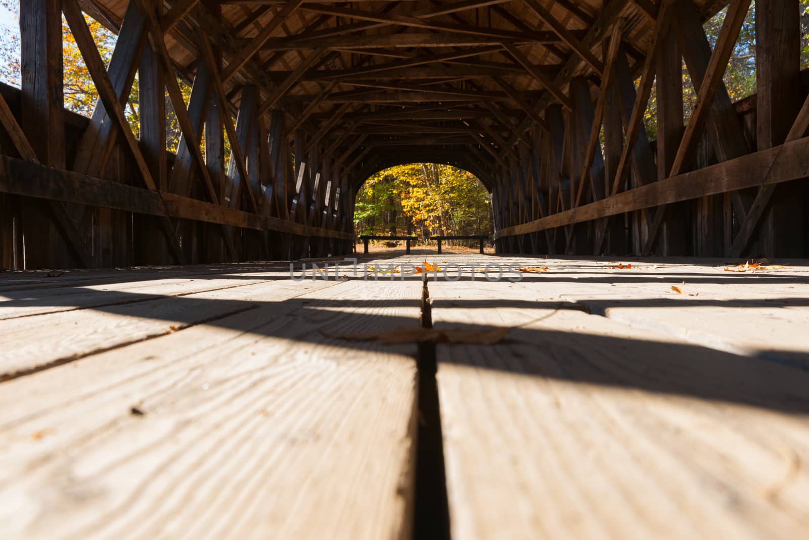 View along platform of Sunday River covered bridge with structure casting shadow pattern and leading lines. Sunday River, Maine, USA.