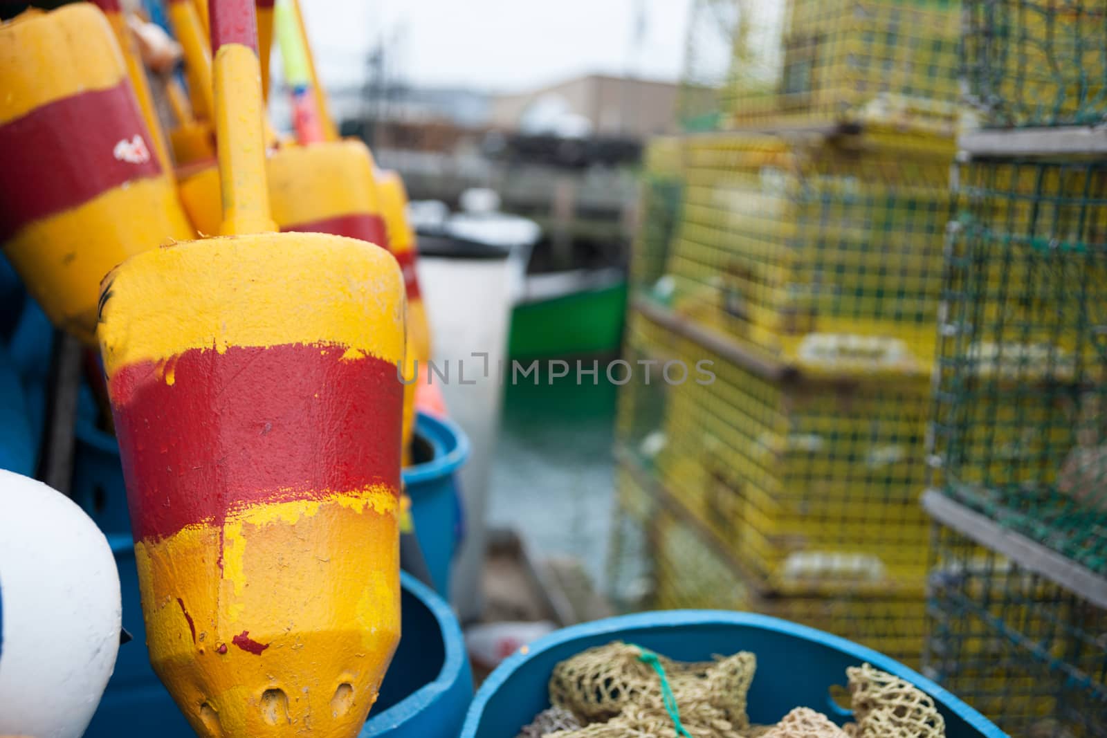 Bright colored buoys in selective focus alongside other equipment and crab traps in port.