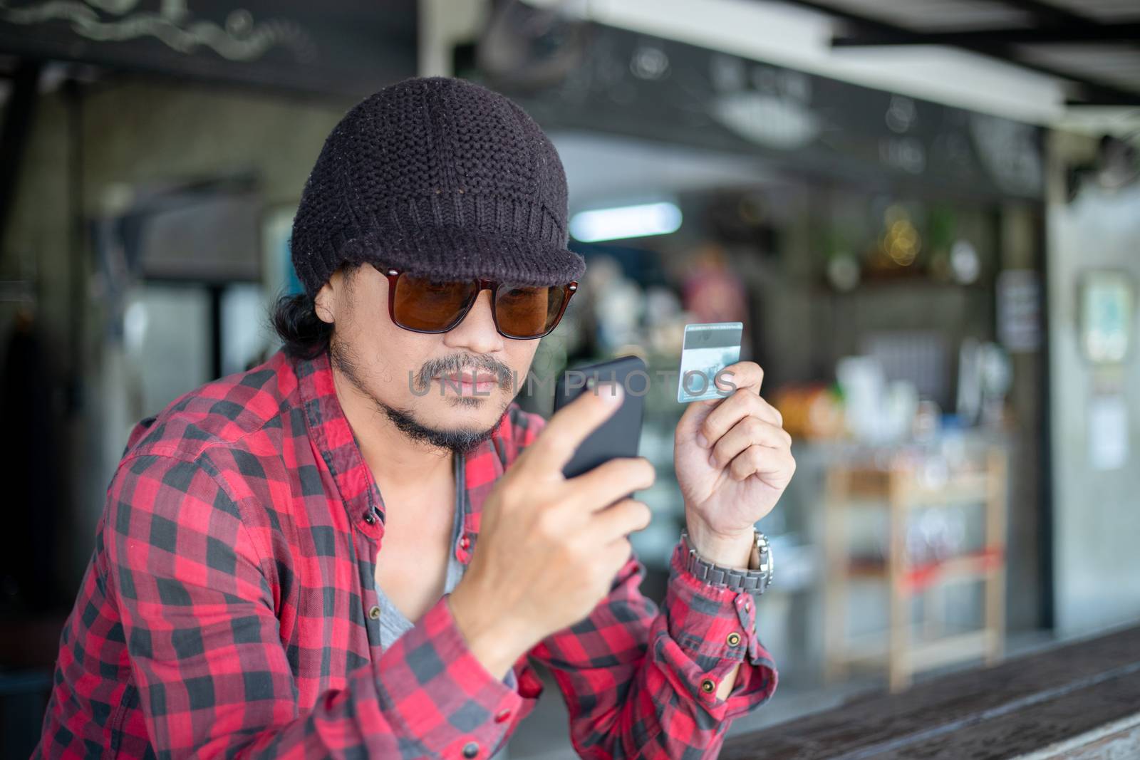 Asian hipster man  are holding credit cards and using  mobile phones for online shopping.