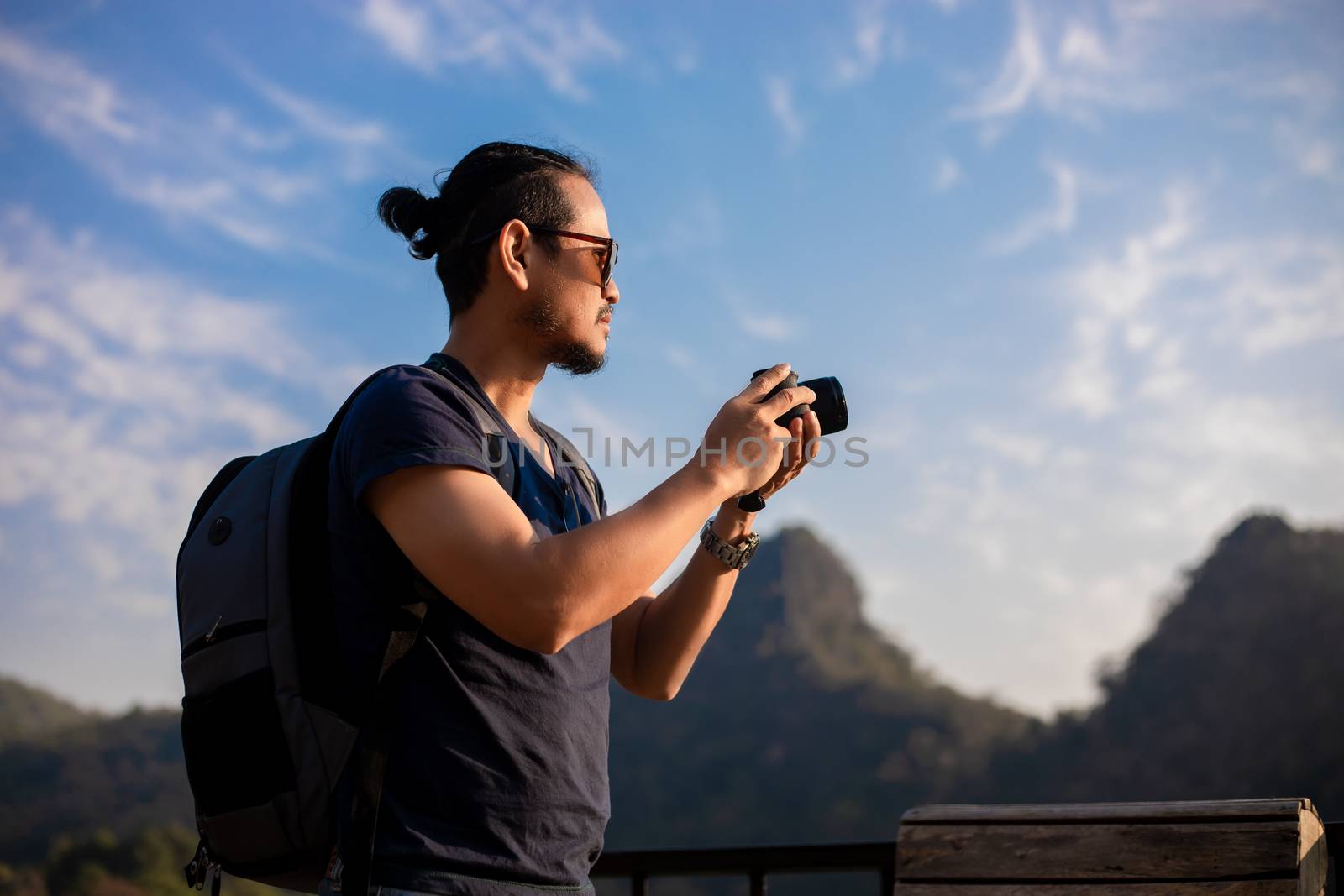 Asian man tourist is using a camera for taking pictures of scenery and mountain .Relax time on holiday concept travel