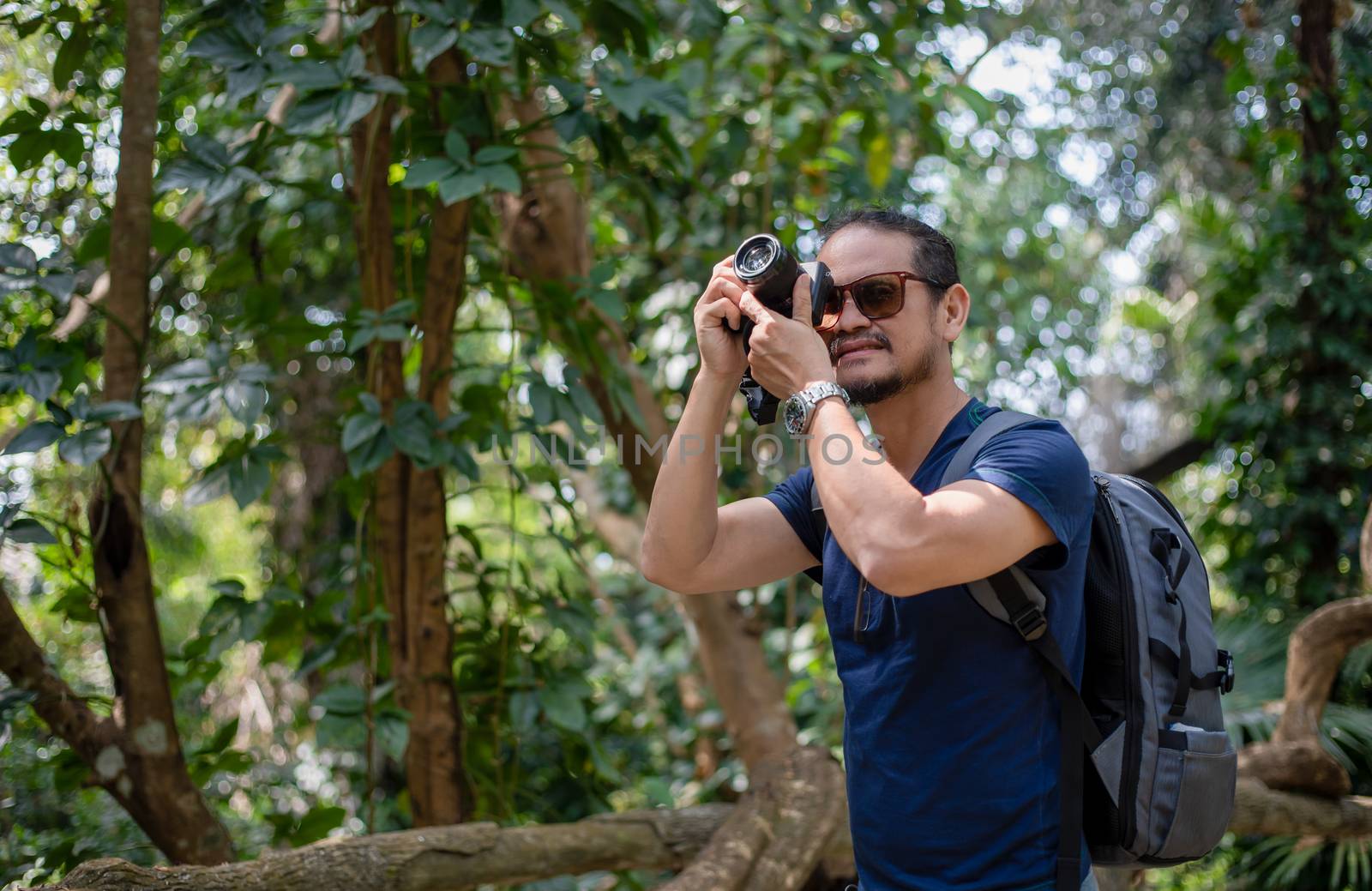 Asian men backpacks and traveler walking together and happy are taking photo on forest ,Relax time on holiday concept travel