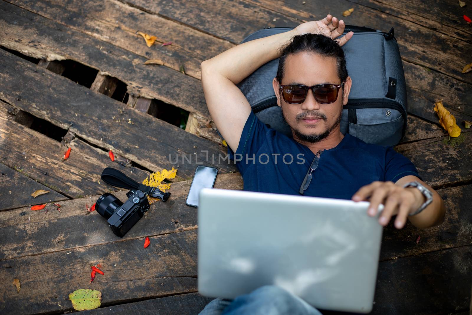 Asian men backpacks and traveler working on computer laptop at outdoor nature and He is relaxing and enjoying on travel