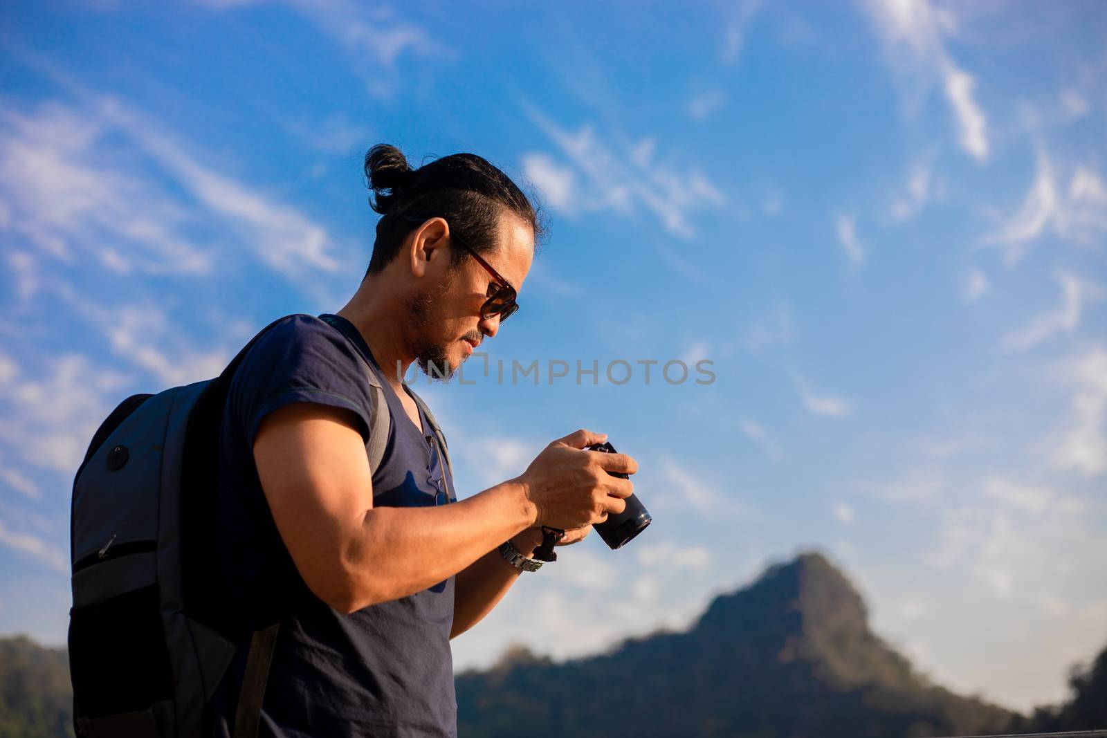 Asian man tourist is using a camera for taking pictures of scenery and mountain .Relax time on holiday concept travel