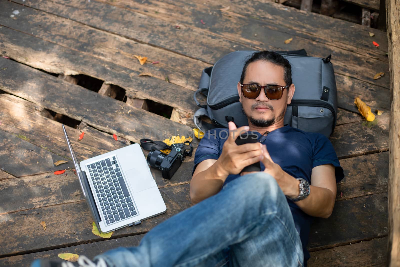 Asian men backpacks and traveler working on computer laptop at outdoor nature and He is relaxing and enjoying on travel