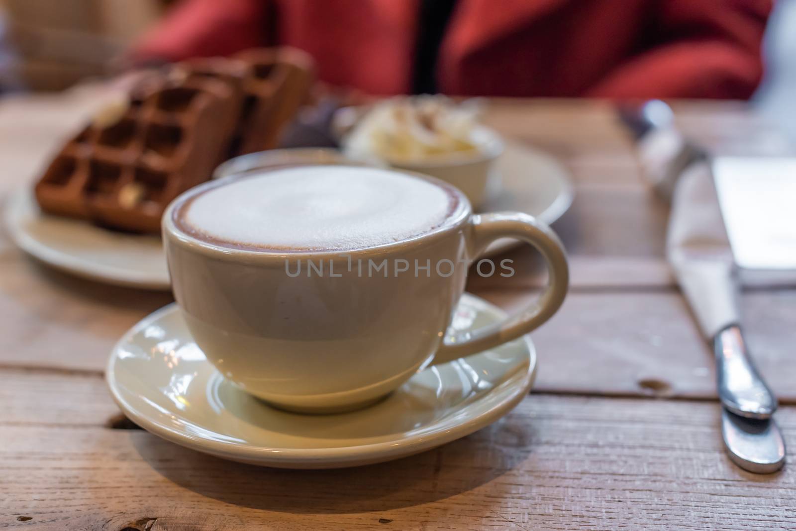 Cup of cappuccino with chocolate waffles on a wooden table