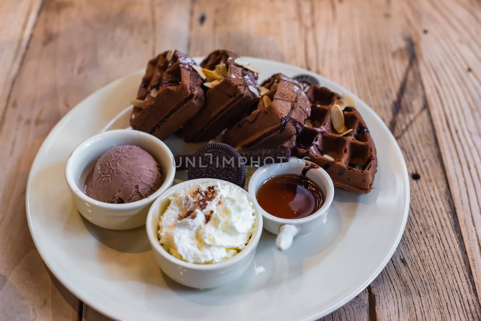 Dish of chocolate waffles with ice cram and honey on a wooden table