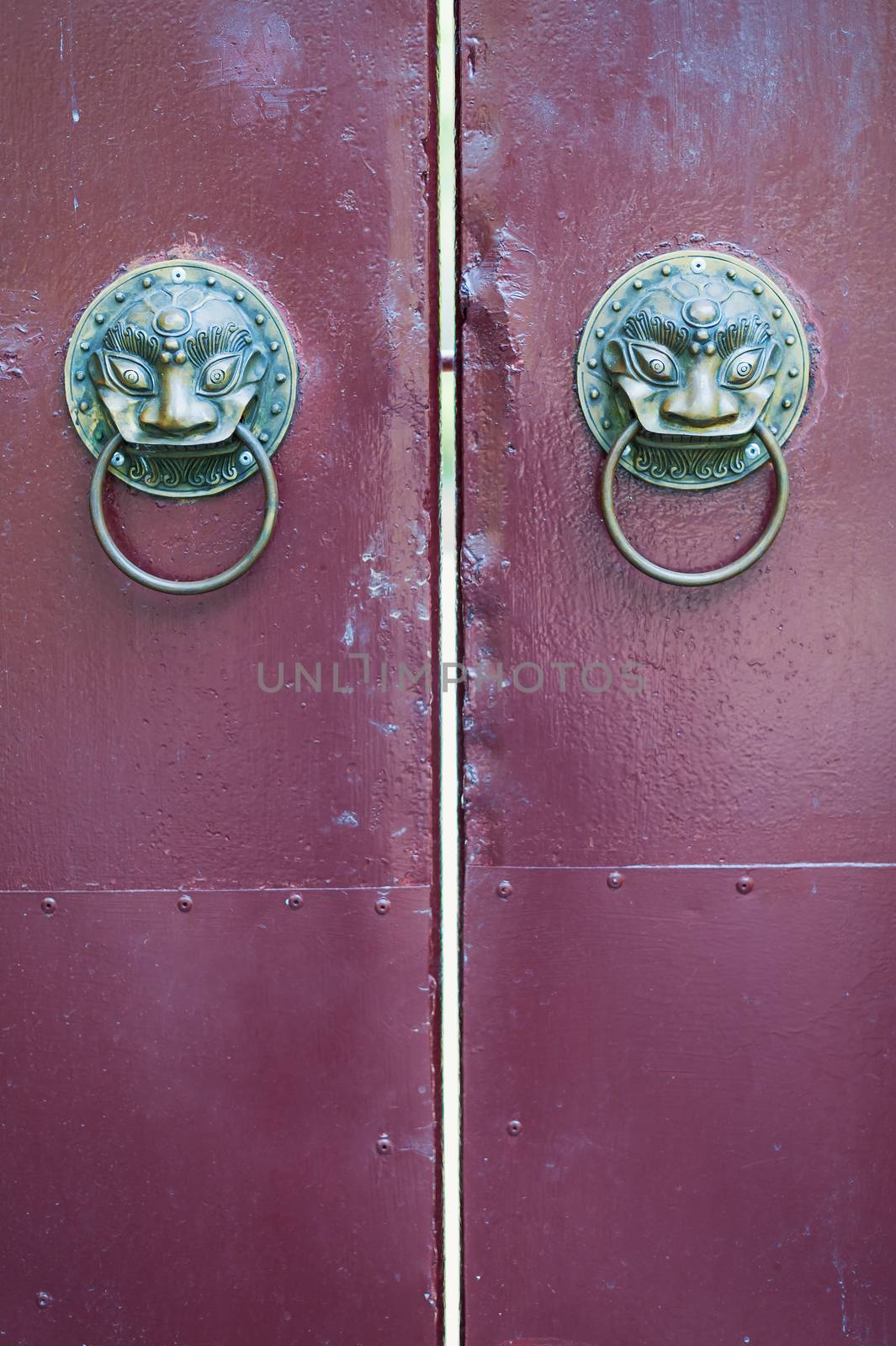 Golden colored chinese door knockers on a red gate