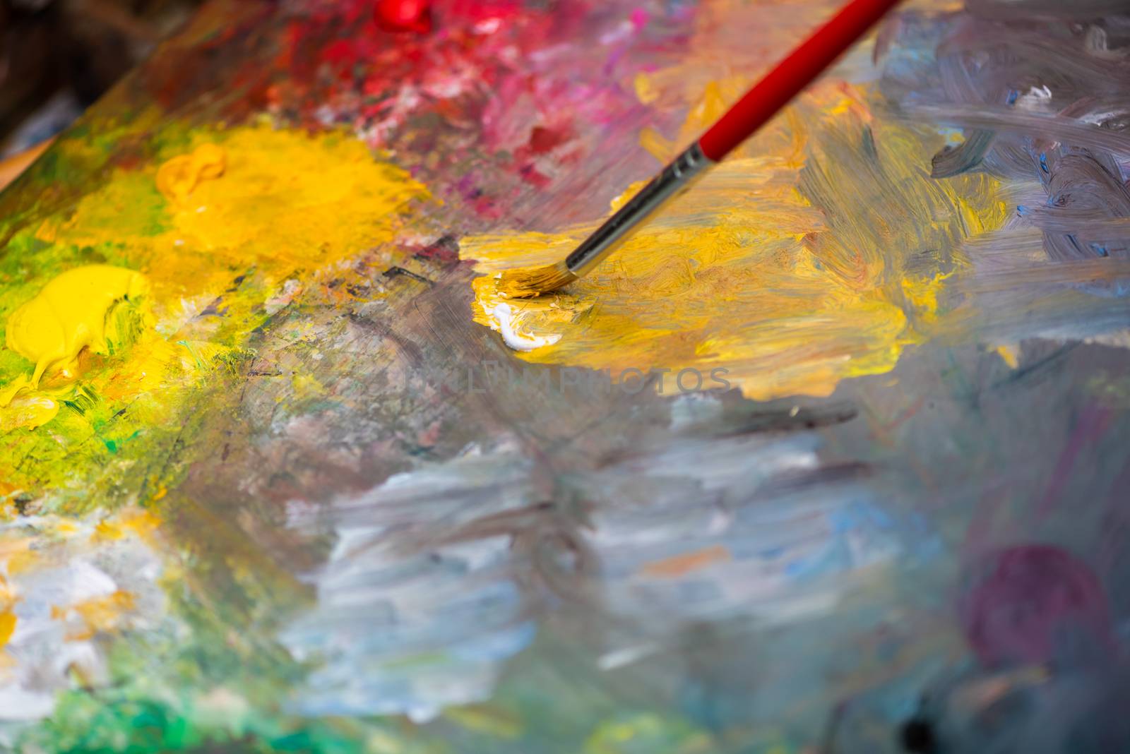 Paint brush on a paint palette with multicolor oil paint