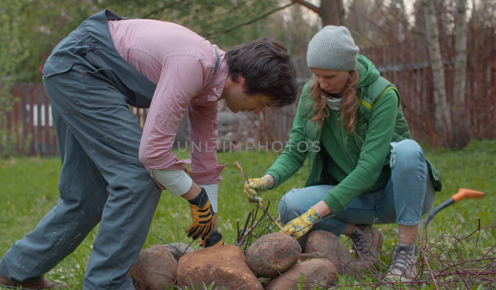 Couple breaking a tree branches for a bonfire. Young handsome family prepares brushwood to light a bonfire in the yard of a country house. People activity and healthy lifestyle concept