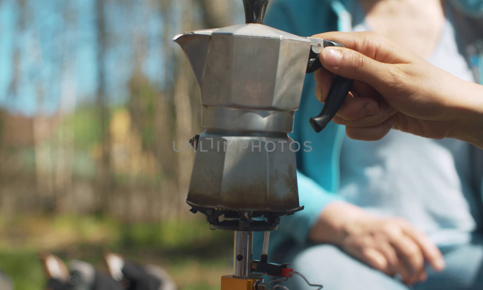 Close up coffee making in the forest on burner. Female hand putting espresso maker on the burner. Healthy lifestyle concept