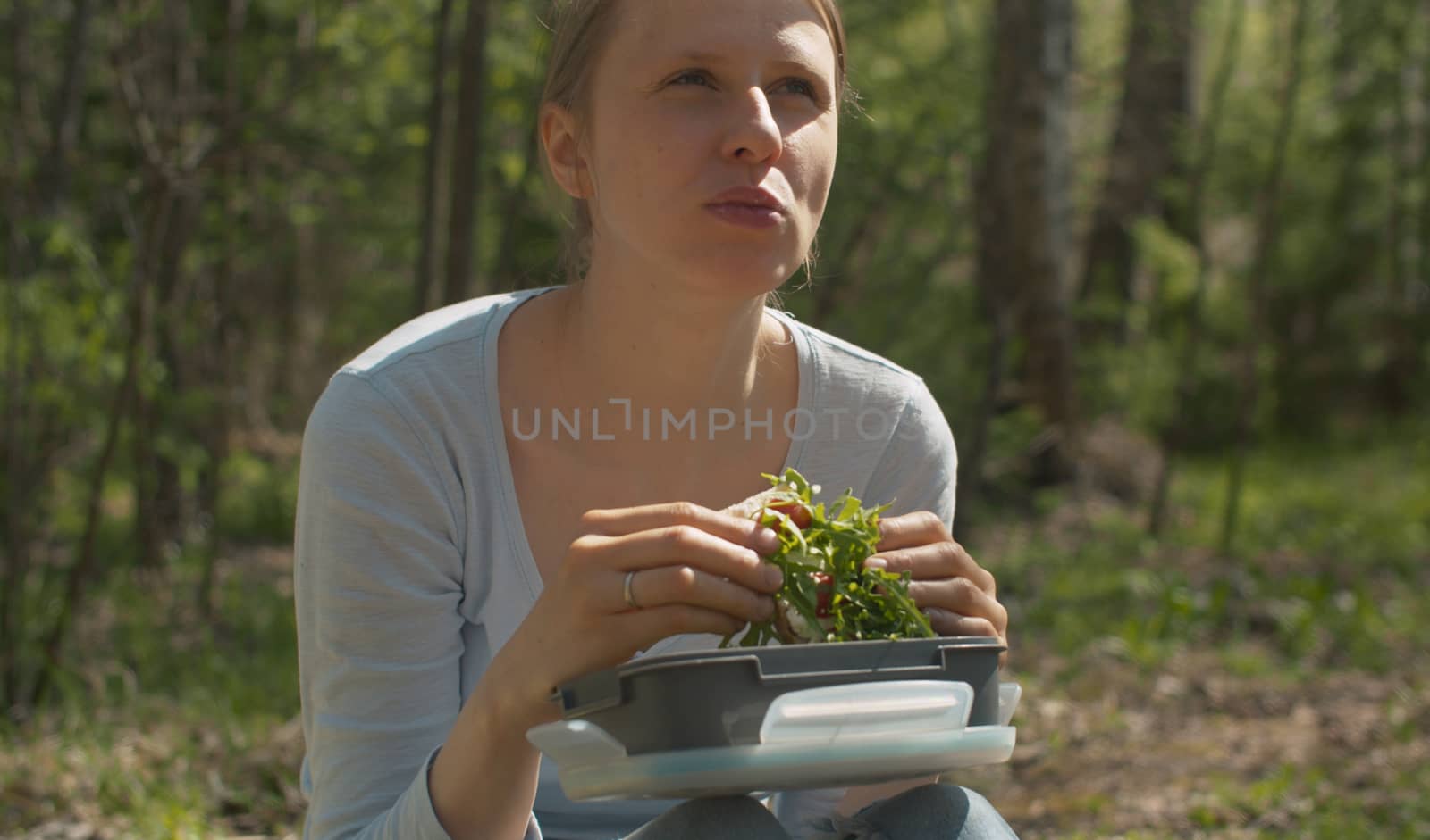 Close up portrait of attractive young woman on a camp eating sandwich. Nice sunny day in the forest. Healthy lifestyle concept