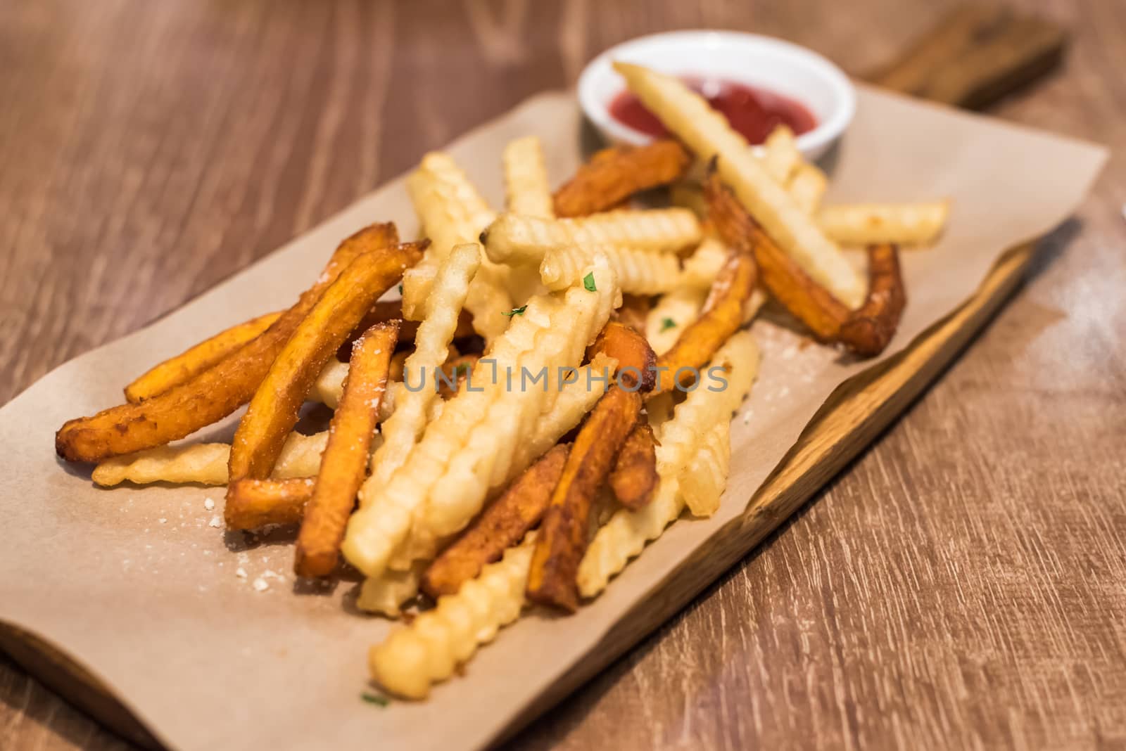 Bunch of french fries with ketchup sauce on a wooden table