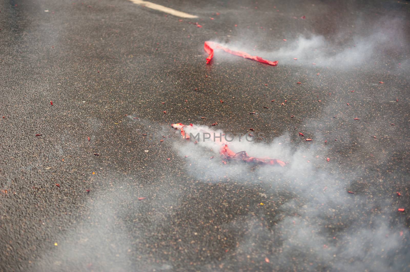 Red firecrackers exploding with smoke on the asphalt by LP2Studio