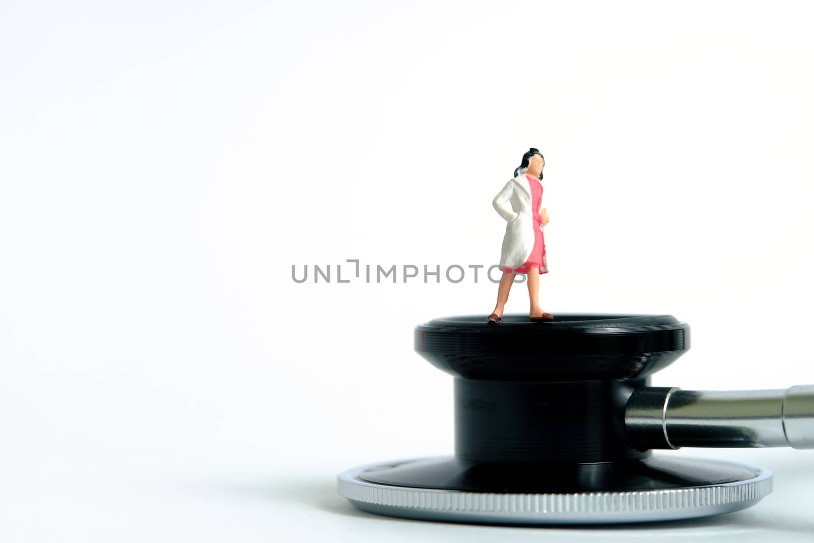 Health conceptual miniature people photography – women doctor stands above stethoscope by Macrostud