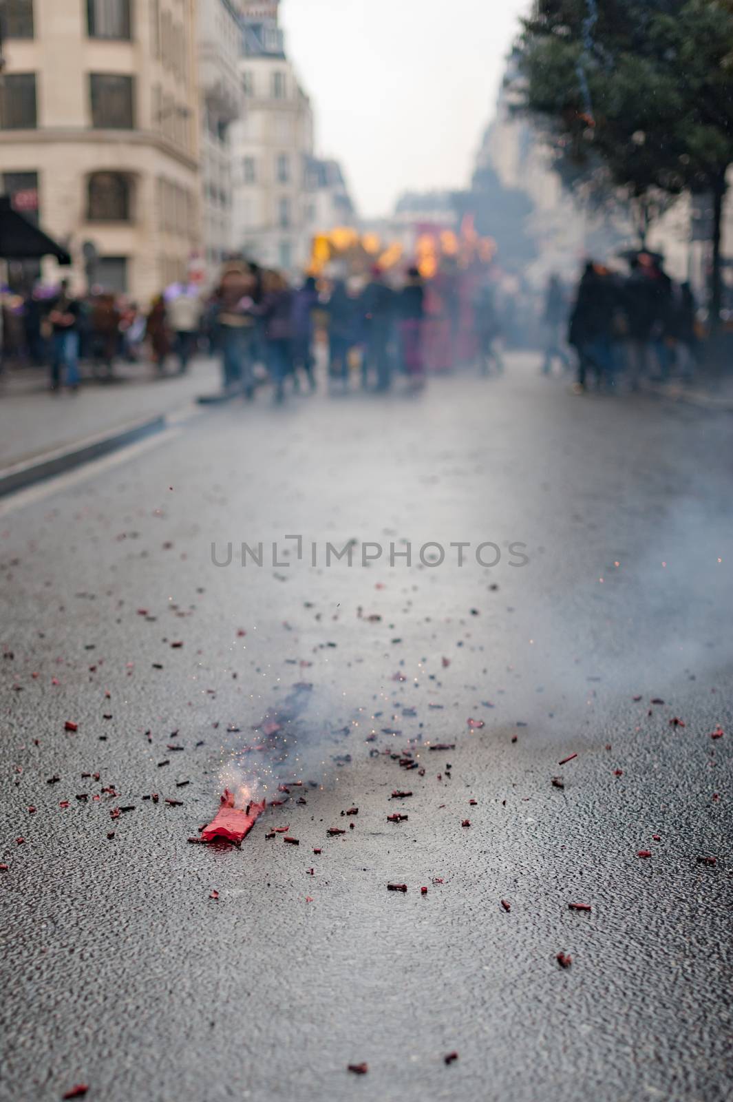 Red firecrackers exploding with smoke on the asphalt with peolple in the background for the chinese new year