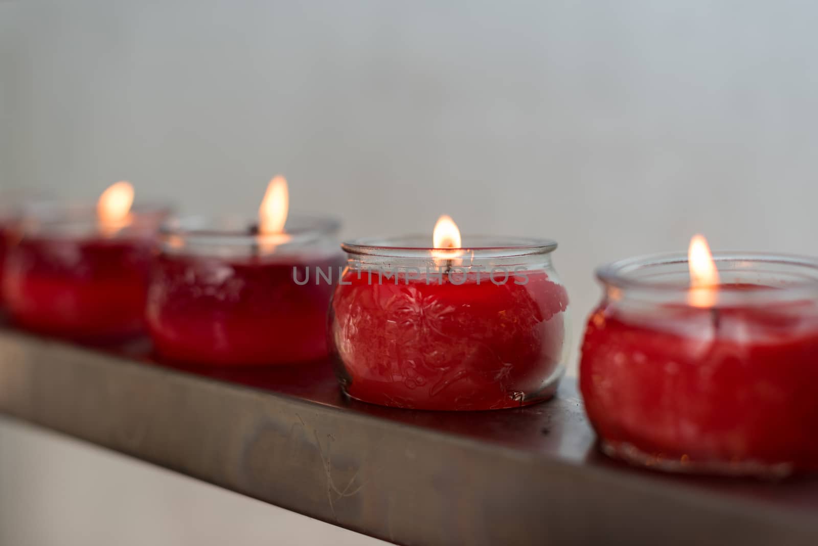 Four red candles in glass cups in row in a buddhist temple, Chengdu, China