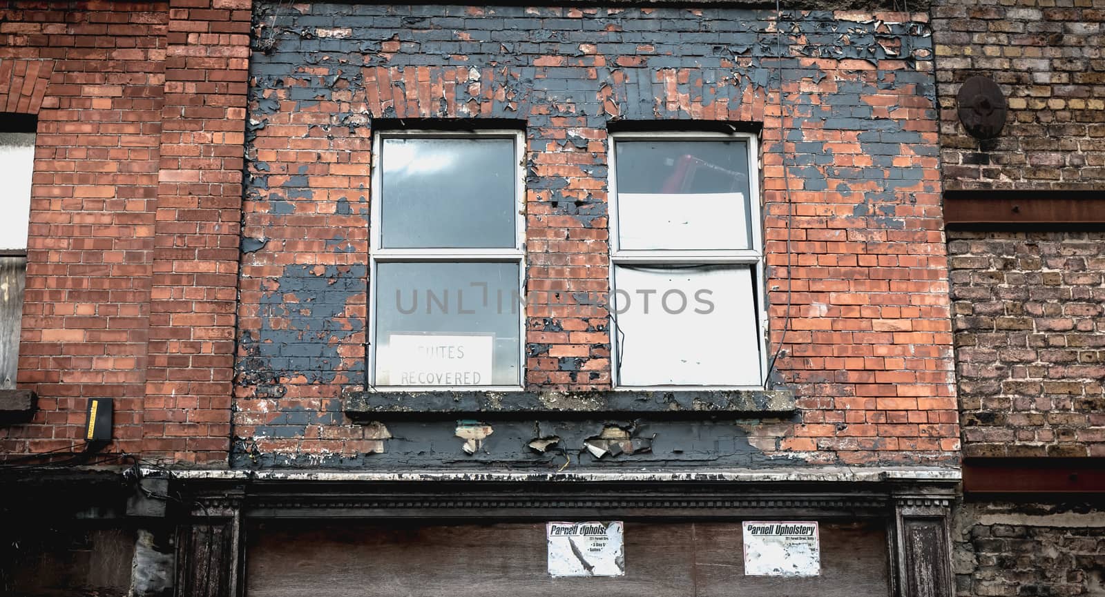 Dublin, Ireland - February 12, 2019 - suites recovered on a panel behind the window of an old dilapidated downtown building on a winter day