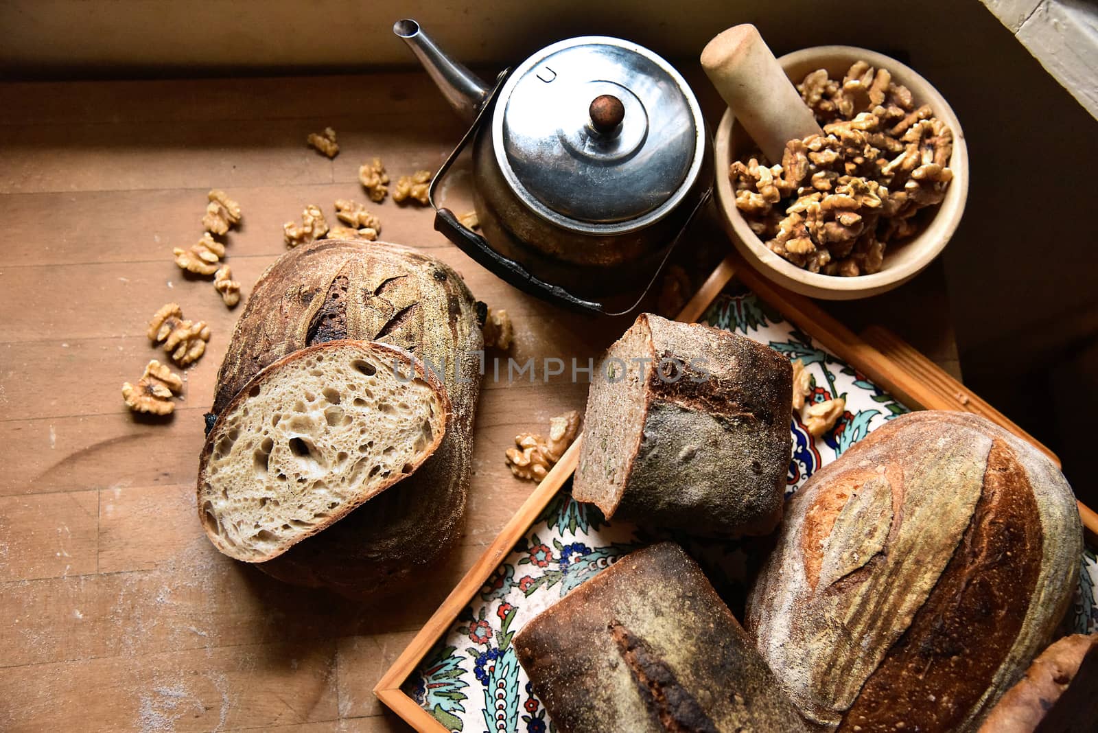 A fresh crusty loaf of homemade bread. Homemade rustic sour. Brown bread. Different types of loaves. Sliced Bread. Atmosphere image of a countryside style kitchen.