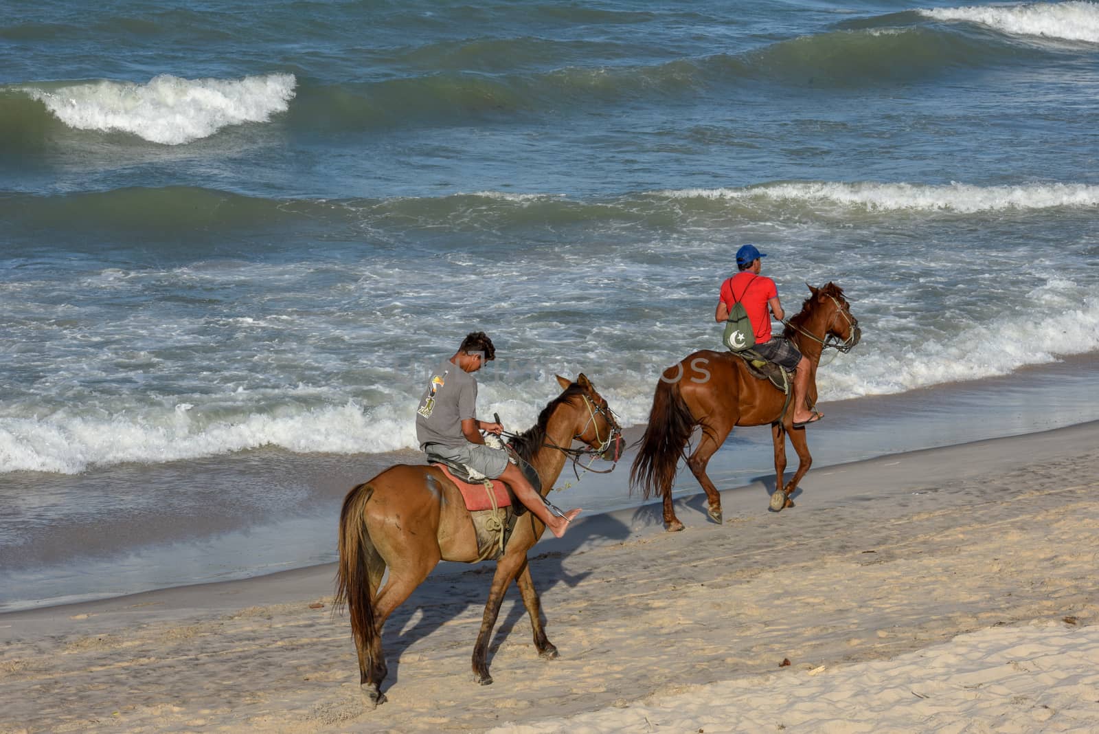 Canoa Quebrada, Brazil - 18 January 2019: pepole riding horses at the beach of Canoa Quebrada on Brazil