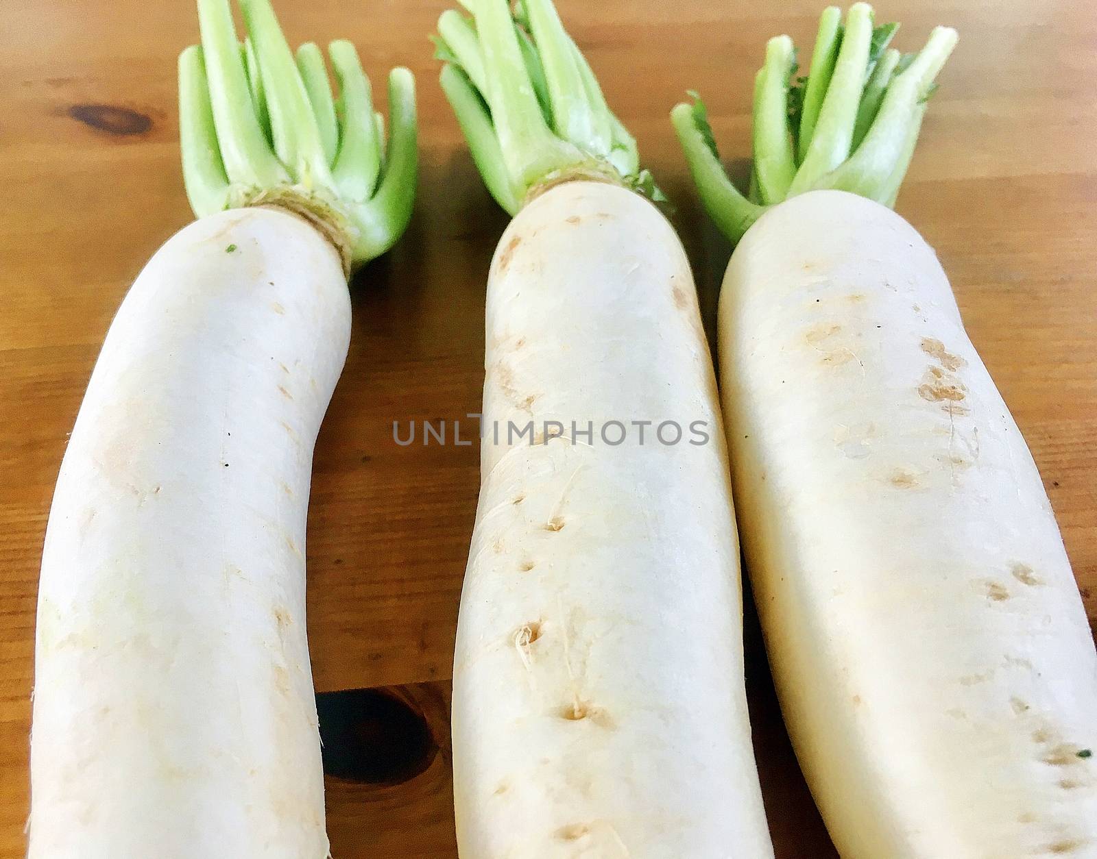 Fresh three white radishes putting on the wooden table in kitchen